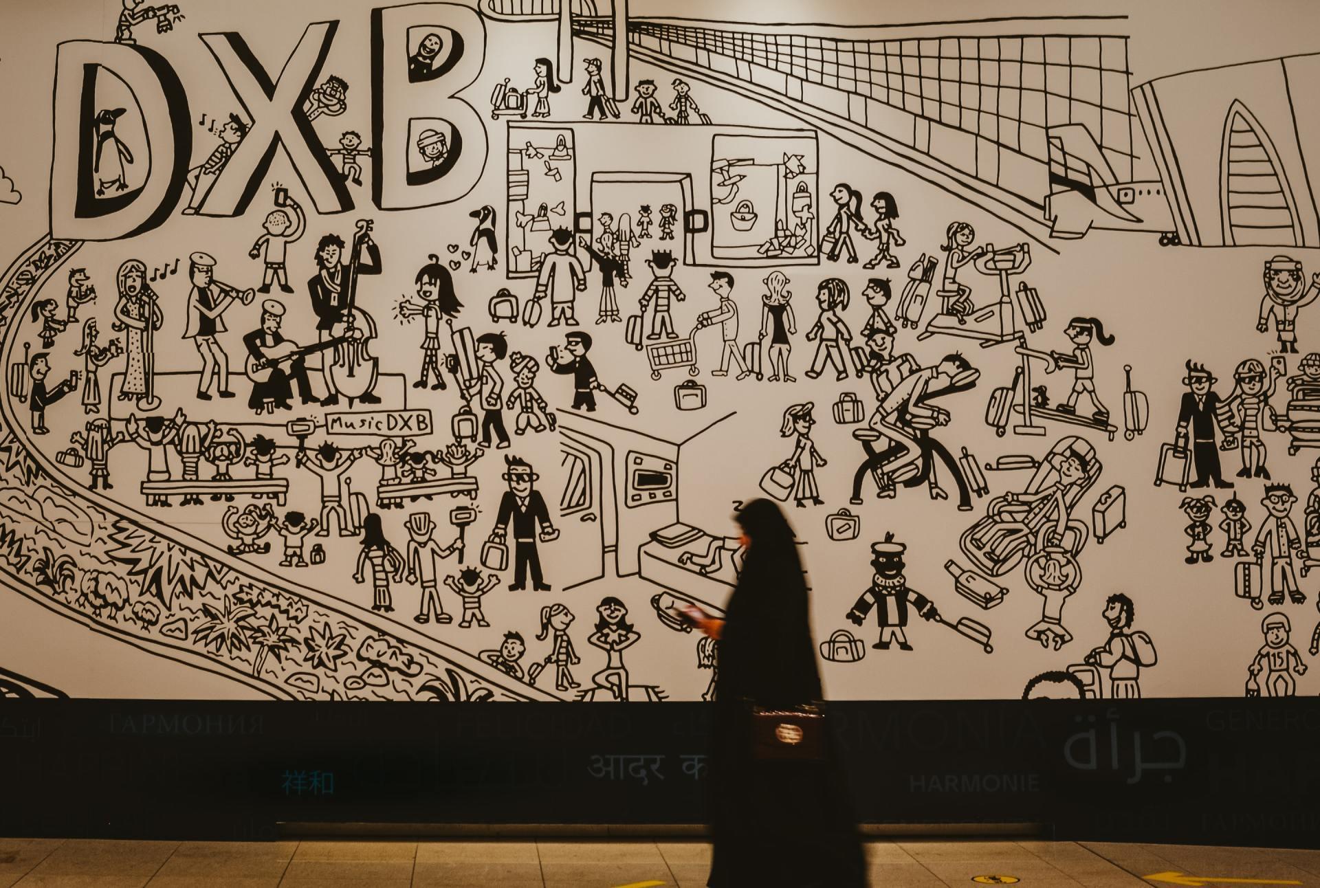 Muslim women walking past a mural in Dubai