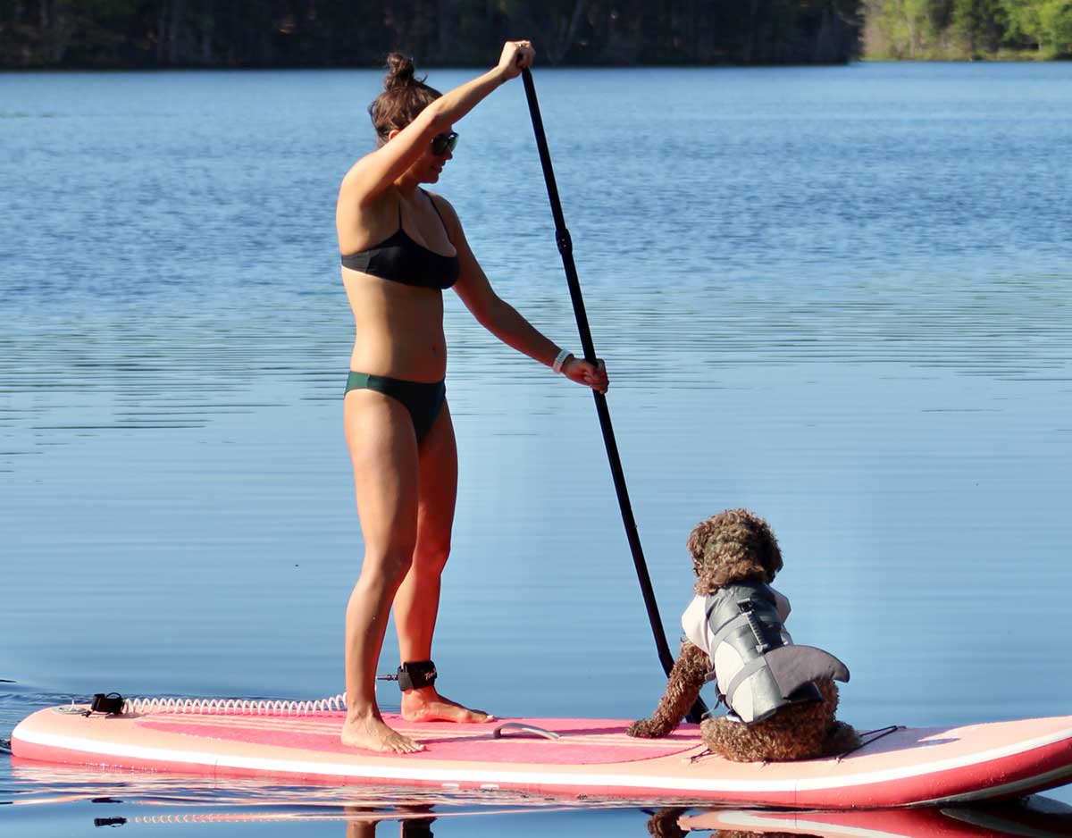 WomanAndDog-SUP-SM Woman and dog with life jacket on paddleboarding